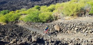 Empujando la bicicleta de montaña por la Montaña Negra de piedras volcánicas en Tenerife por Comunidad Biker MTB